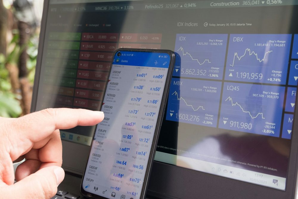 Hand pointing at currency quotes on a smartphone